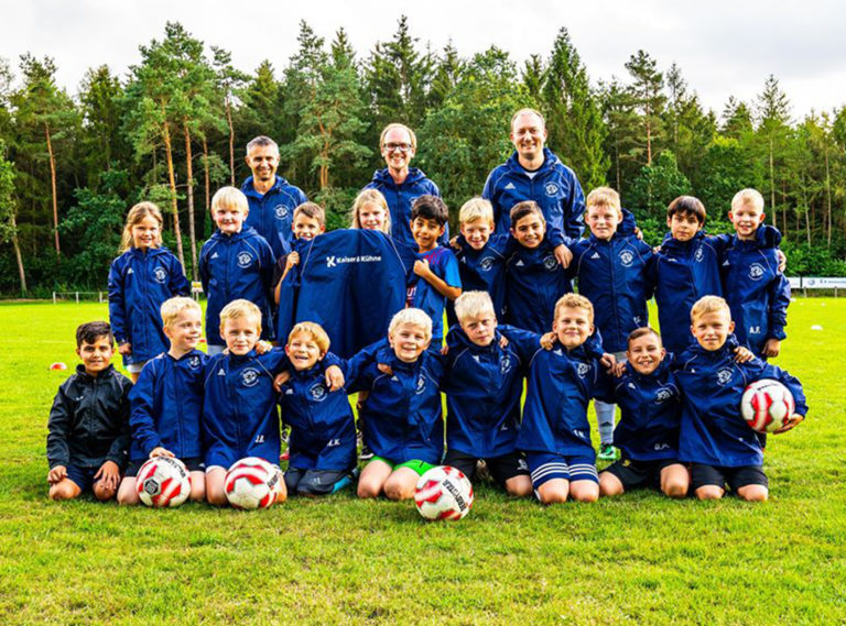 Kleine Jungs spielen Fussball und machen ein Mannschaftsfoto und tragen jacken von Kaiser und Kühne