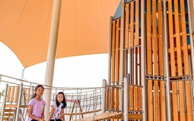 Two girls are sitting on the suspension bridge next to the playground, which leads to the tower