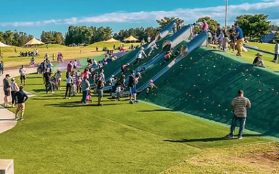 Baxland playground: three slides side by side on a hill, with lots of children playing there