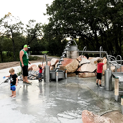 Knudsen Park, ein Junge spiel auf den Spielplatz, auf einem Berg bei dem Gebauten Bach