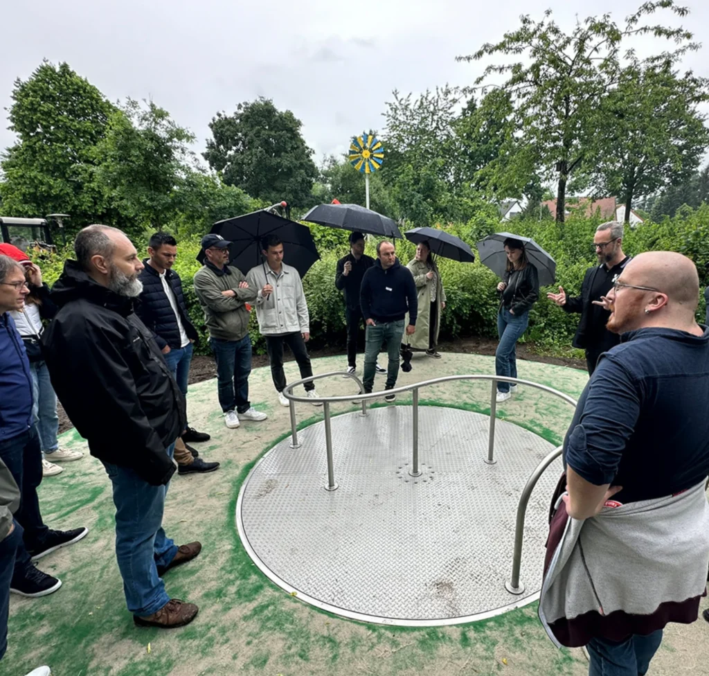 Mitarbeiter von Kaiser und Kühne und der Firma Pro Urba bilden einen Stehkreis um ein Spielgerät 