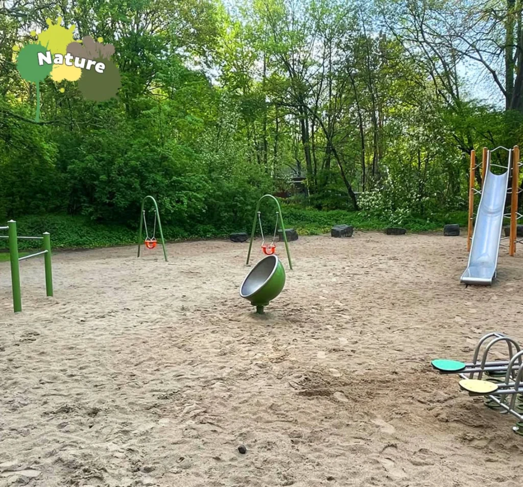 Auf den Spielplatz ist eine Drehkugel im Sand und eine rutsche ist rechts daneben abgebildet