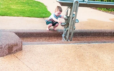 A little boy is playing with a water feature in Playford Park
